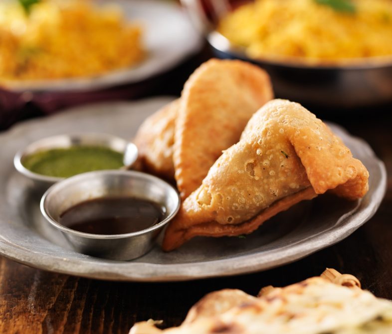 two indian samosa with mint and hot chutney
