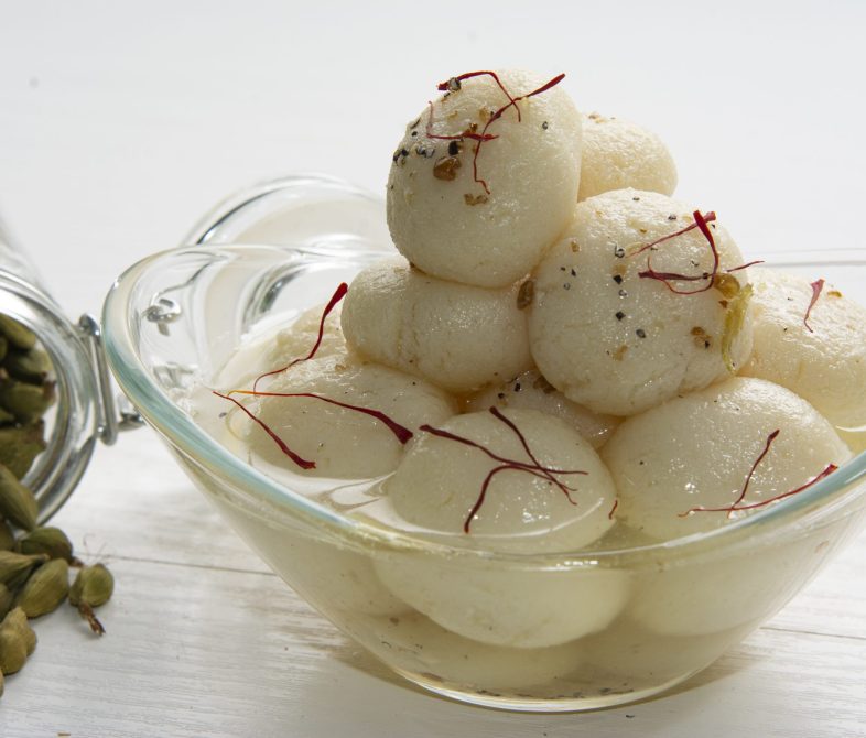 Traditional appetizing ball-shaped dumplings of Rasagulla dessert in light sugar syrup